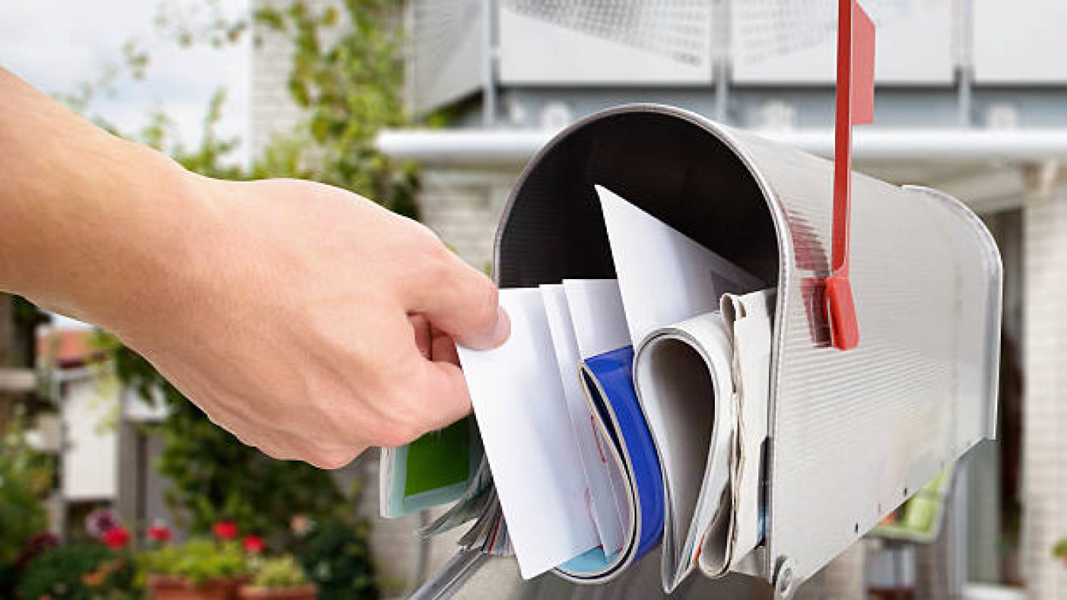 Close-up Of Man's Hand Taking Letter From Mailbox Outside House